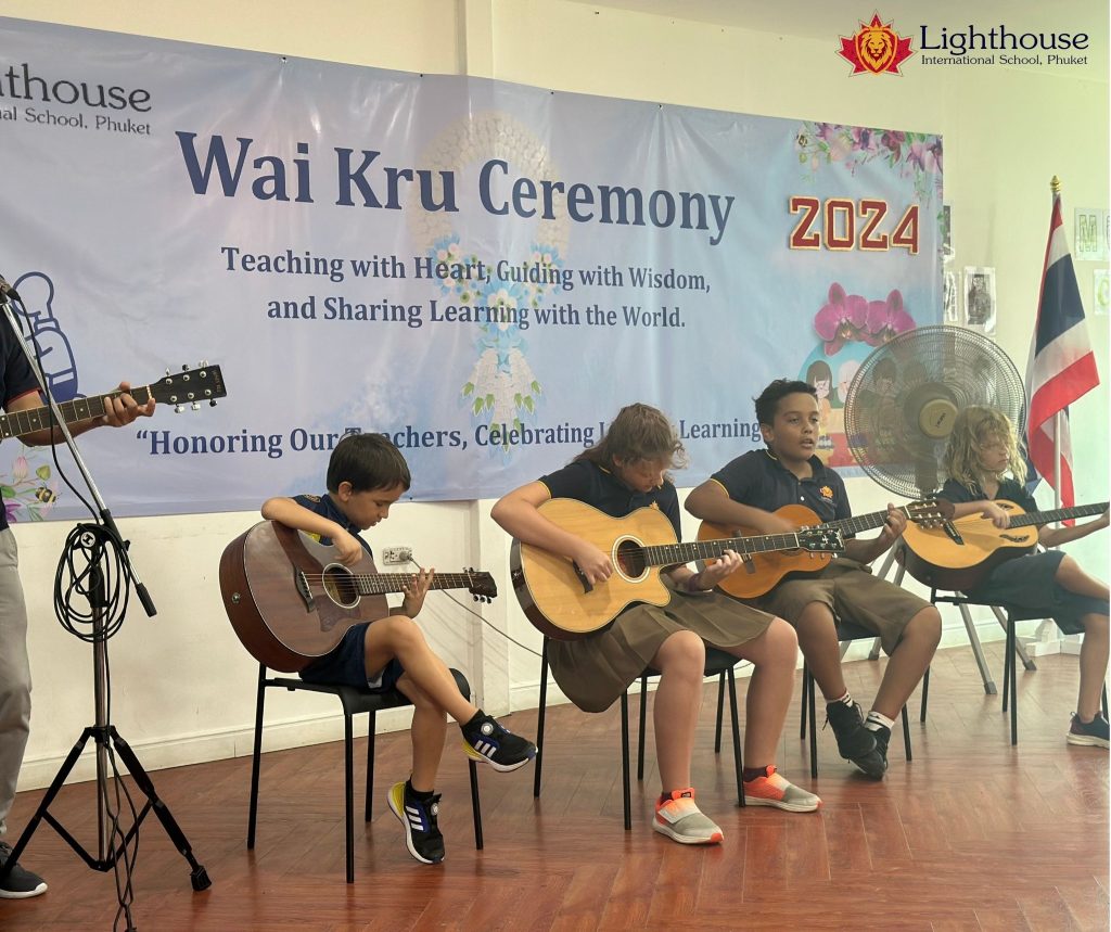 Four students playing a guitar with the teacher as the lead