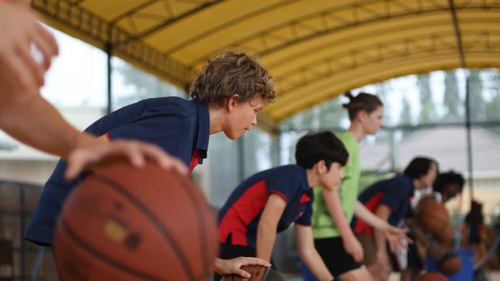 A line up of boys dribbling basketball