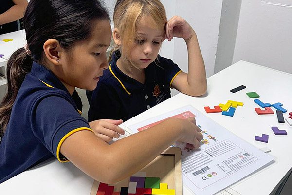 education-maths-primary-class Two girls in primary school figuring out a puzzle together