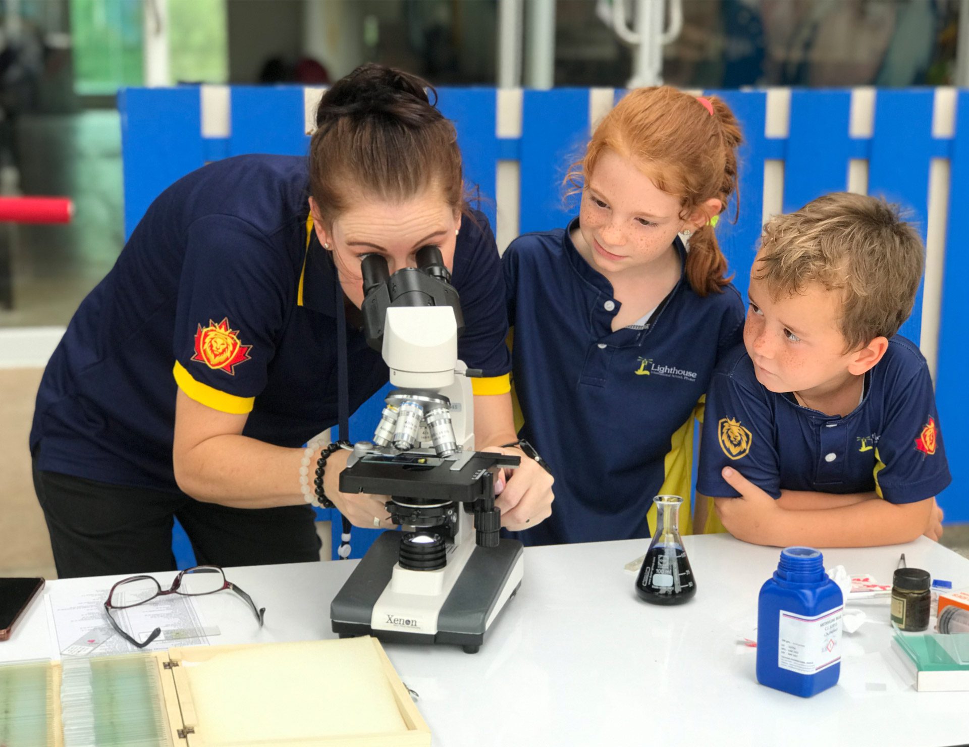 science-lighthouse-primary-school-phuket An image of a teacher looking through the microscope, teaching the primary students