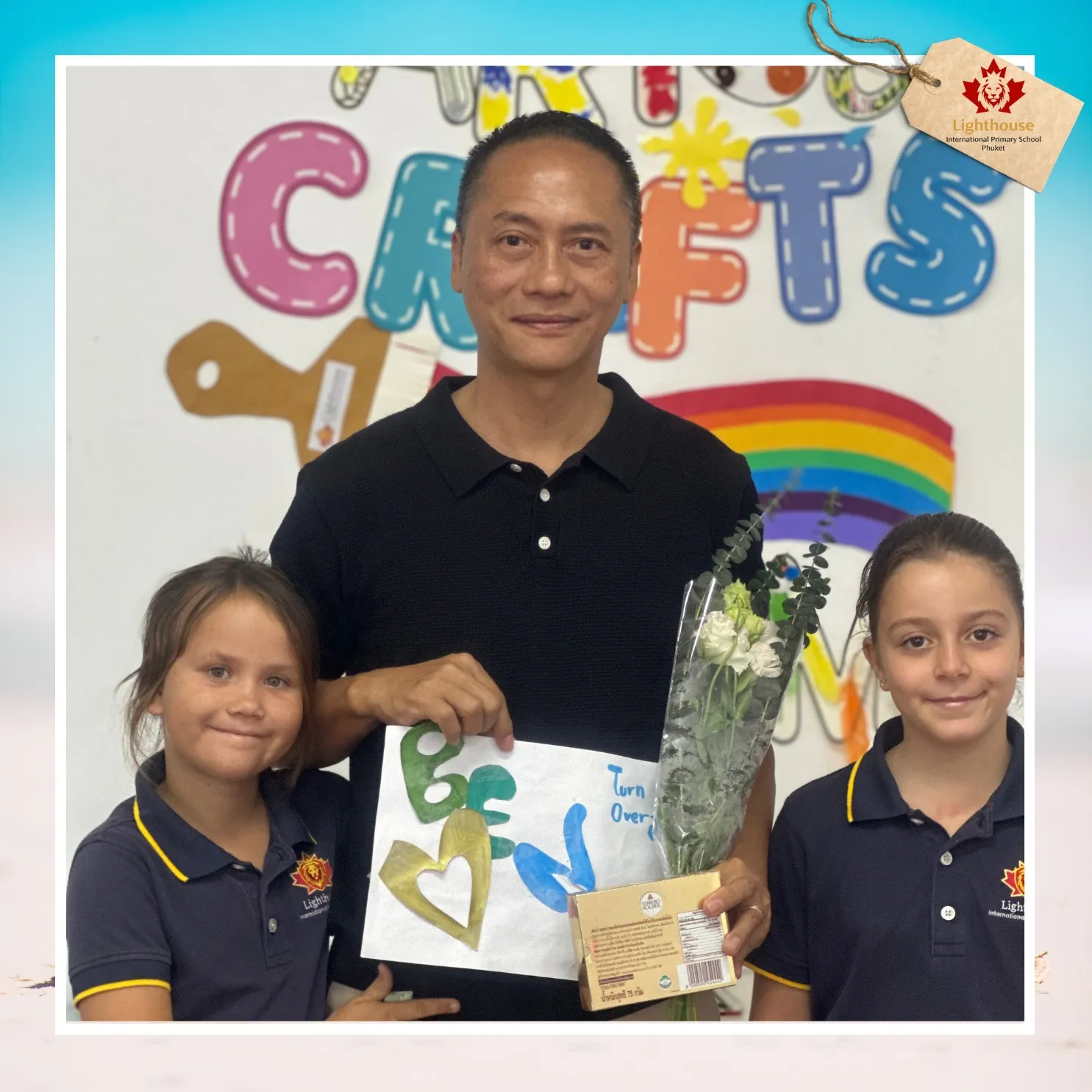 Girls posing with a teacher holding card and flower