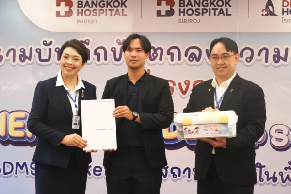 Three people holding a guide book and a box, standing in front of a tarp