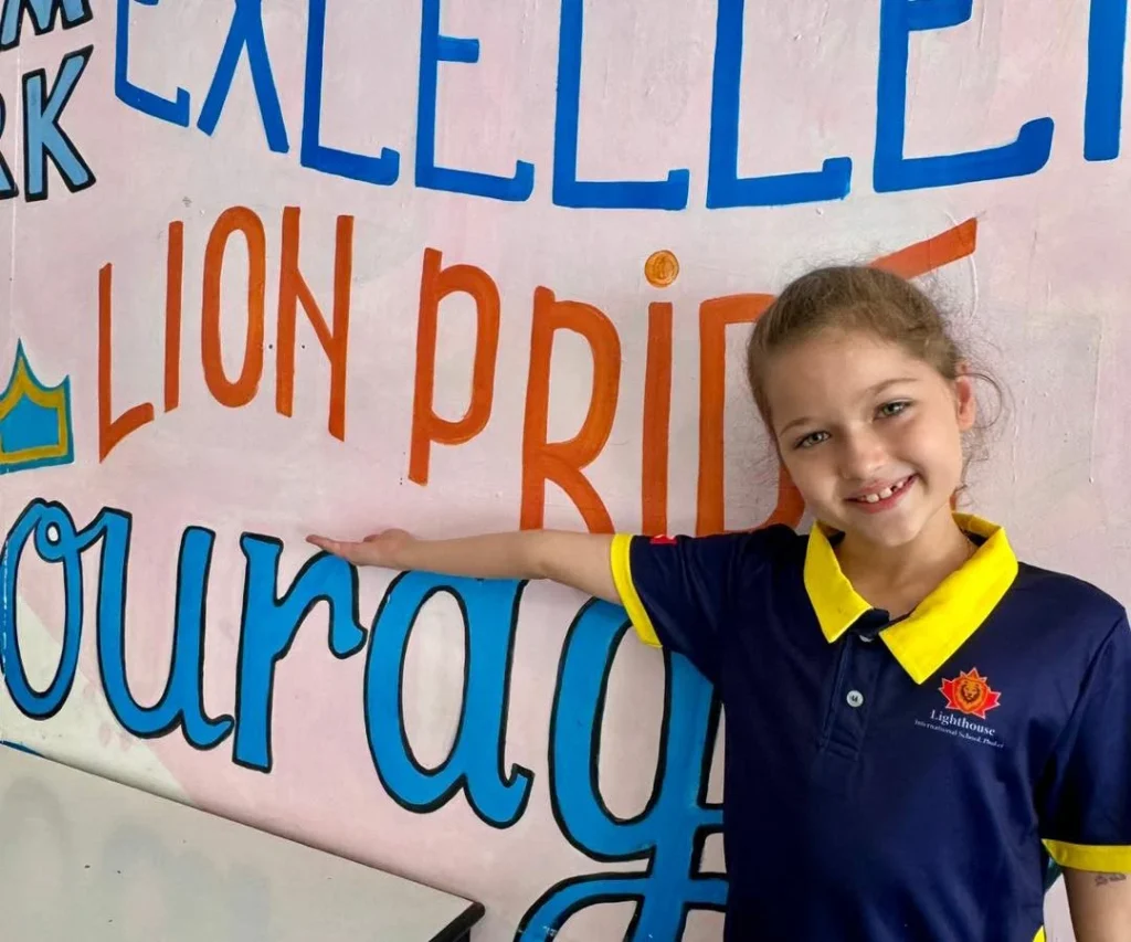 Lighthouse Student posing beside a Lion Pride mural