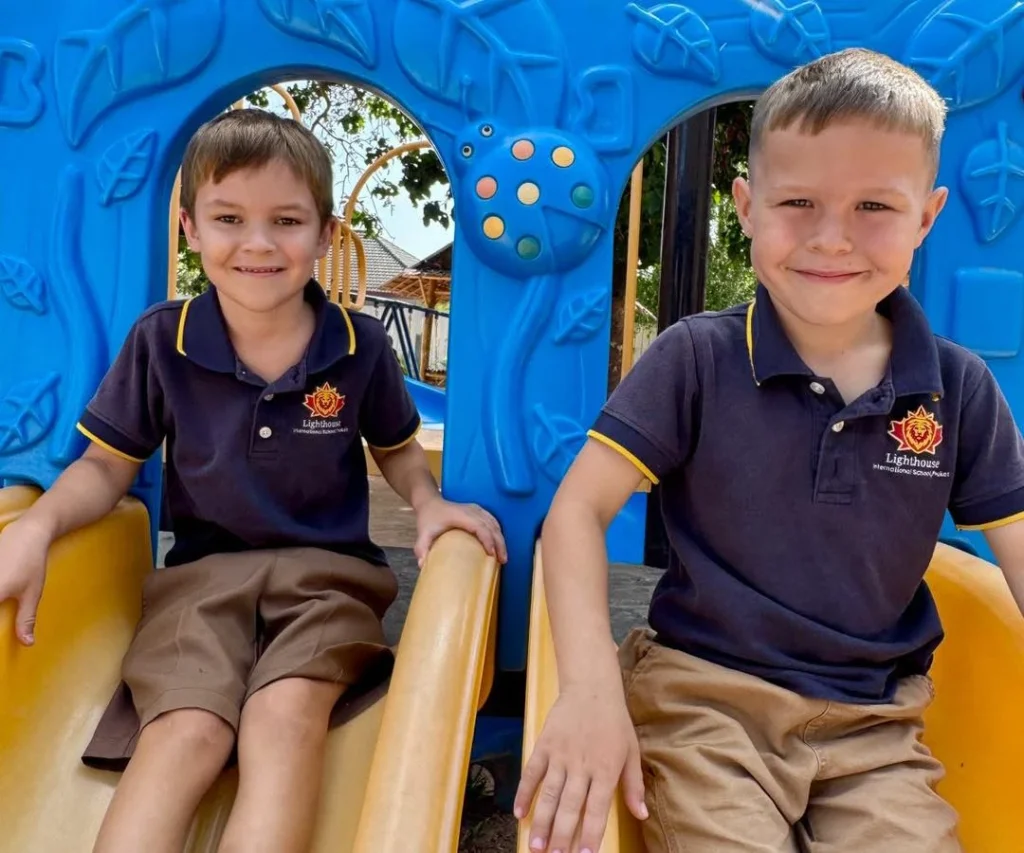 Two boys smiling while on slides