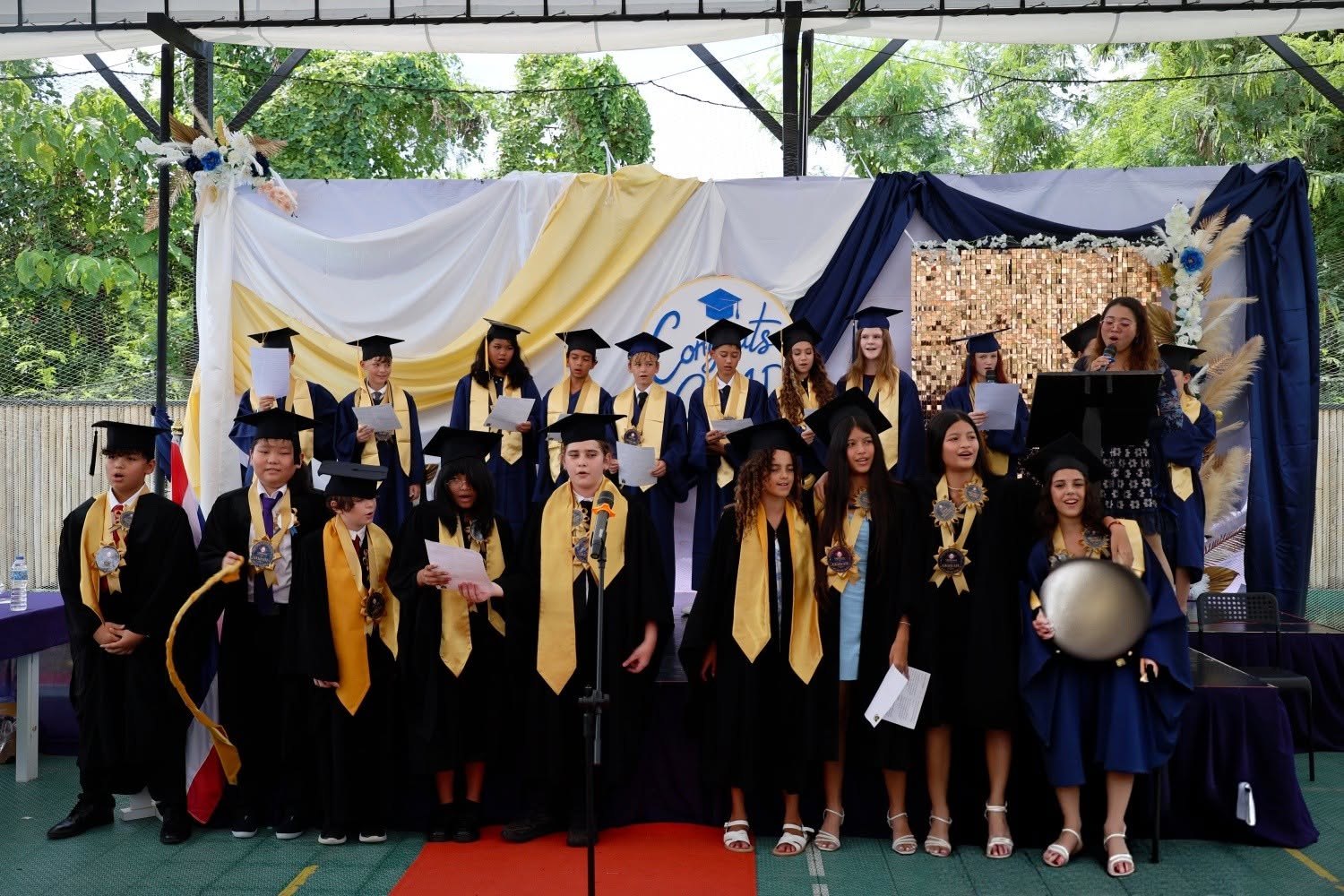 Grade 6 graduates in the stage with their teacher