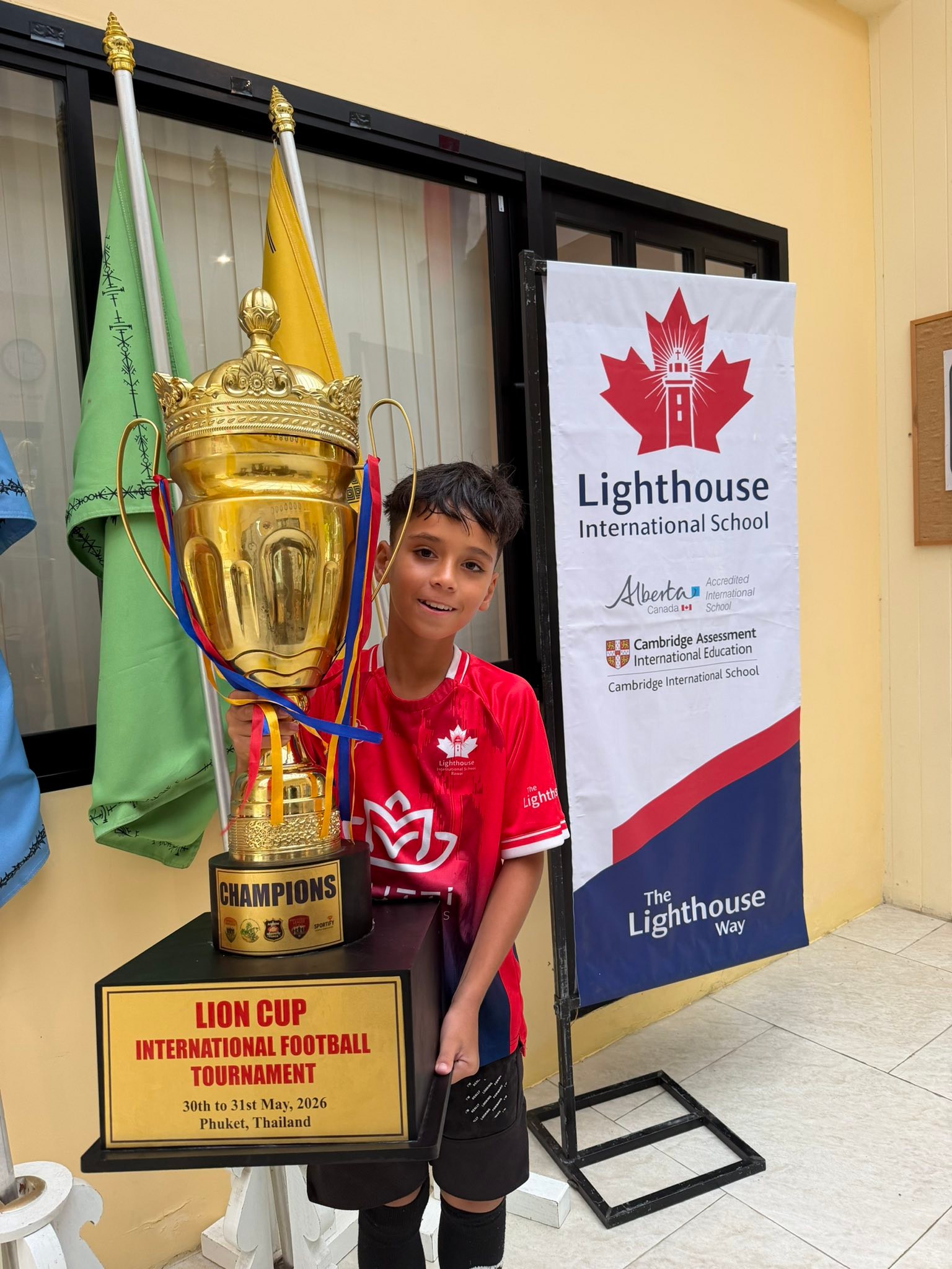 Lighthouse International School student holding a large trophy