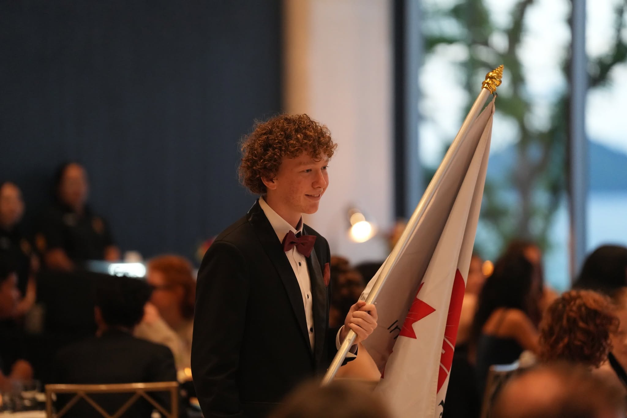 Student in suit, bearing the Lighthouse International School flag