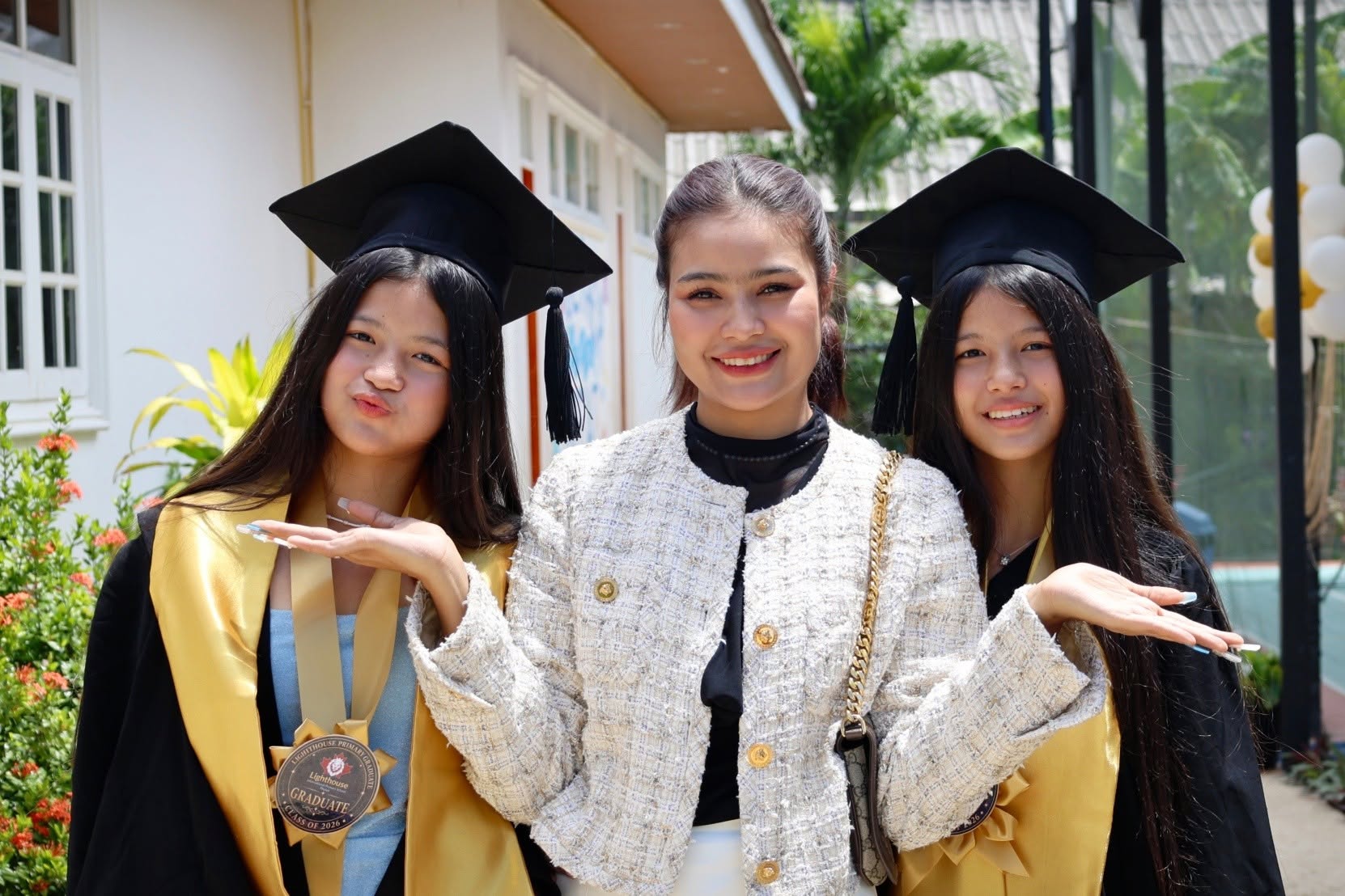 Teacher smiling with her two graduating grade 6 students in Thailand