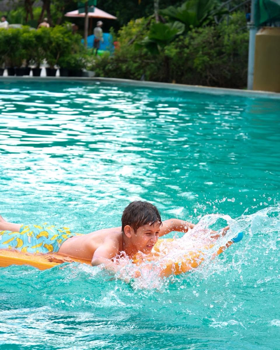 Lighthouse International School boy paddling with a board in the pool for YouTopia Phuket summer camp Lighthouse International School boy paddling with a board in the pool for YouTopia Phuket summer camp