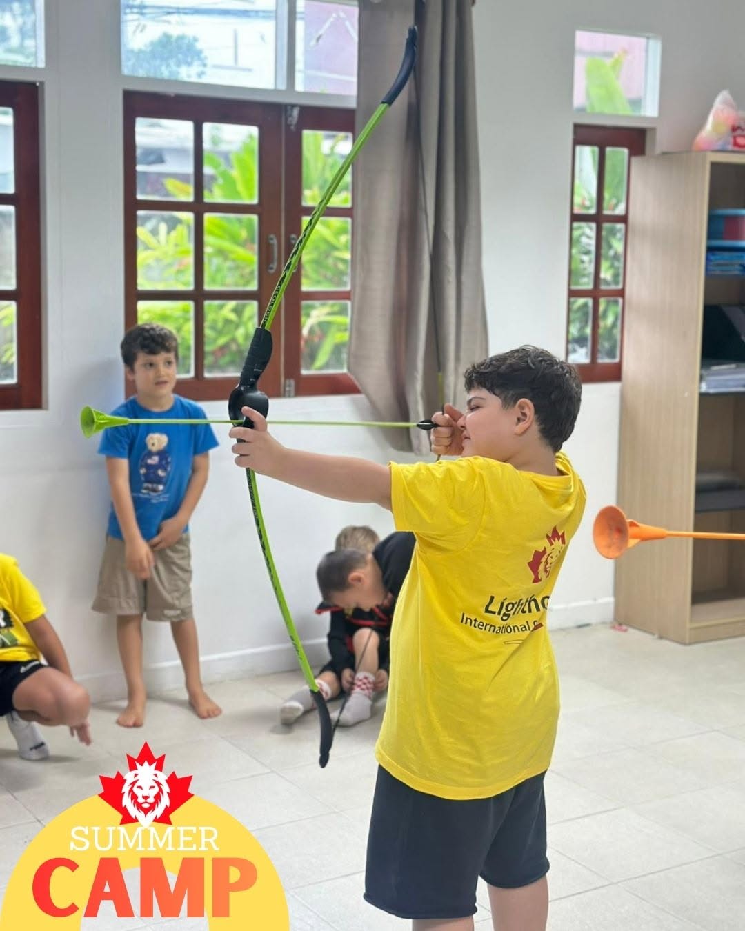 Young boy using bow and arrow toy during summer camp at Lighthouse International School