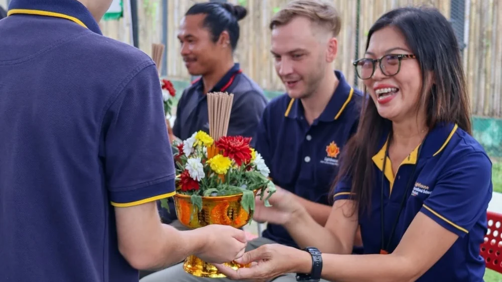 A Lighthouse student handing the teacher a flower arrangement for Wai Kru Day