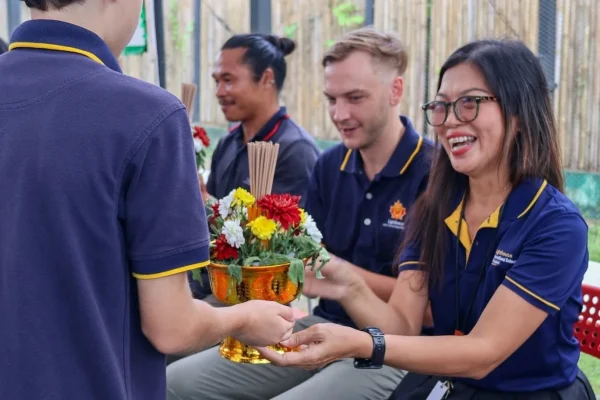 A Lighthouse student handing the teacher a flower arrangement for Wai Kru Day