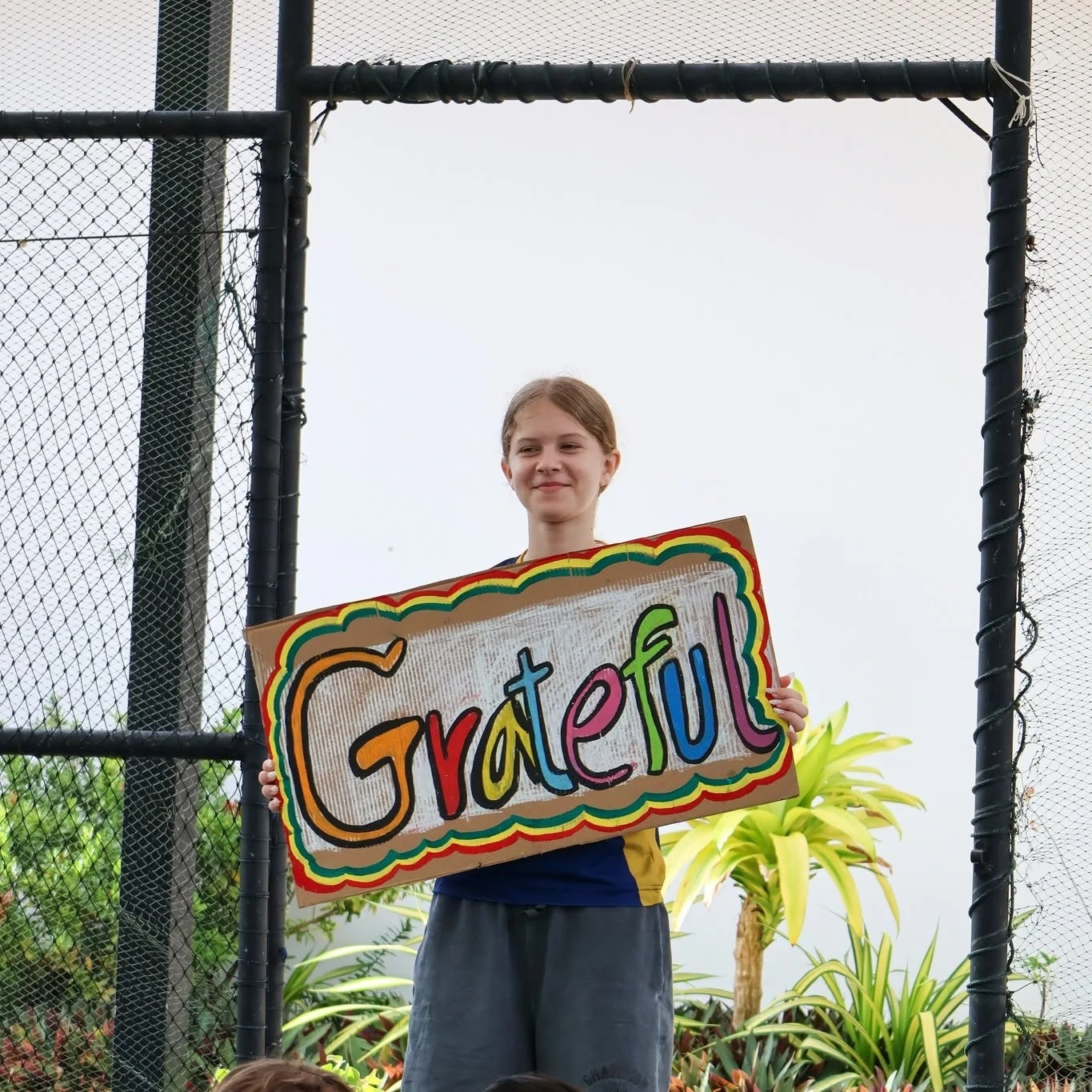 A Lighthouse student holding a colorful Grateful sign