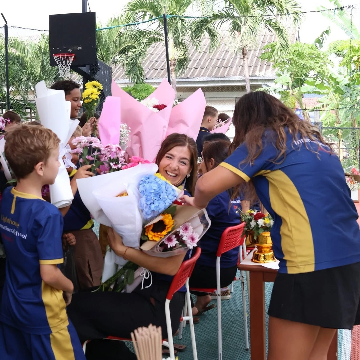 Lighthouse teacher holding numerous bouquets for Wai Kru Day