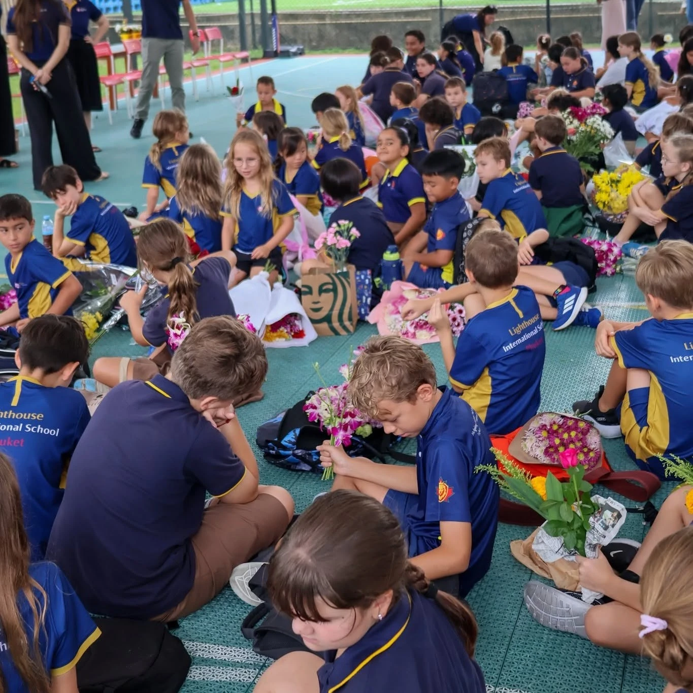 Primary students of Lighthouse International School sitting cross-legged on the gym floor