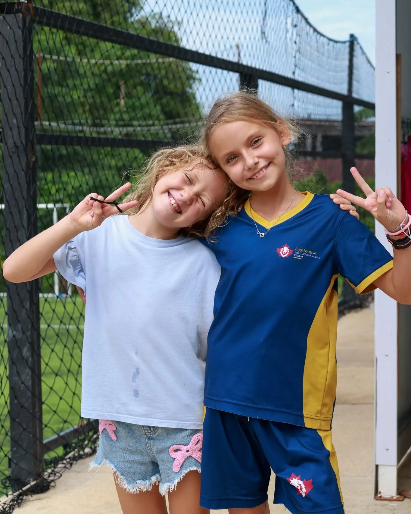 Two girls doing a peace sign as they smile for the camera during World Peace Day Two girls doing a peace sign as they smile for the camera during World Peace Day
